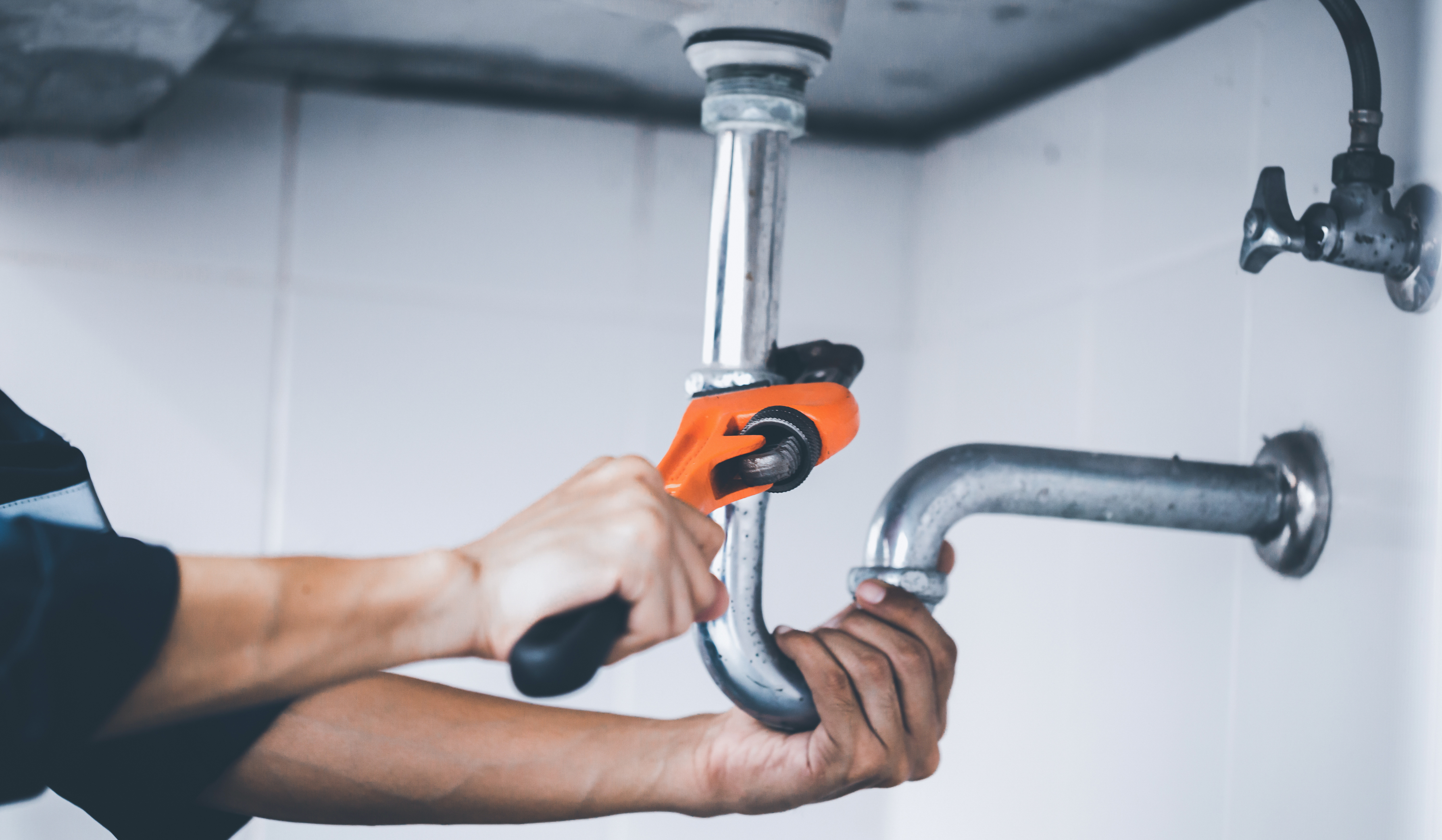 Plumber working on pipes under a sink