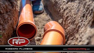 Plumber Laying Drainage Pipes into the Ground